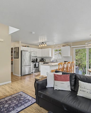 Bright bedroom with wood bed, dining table, glass doors overlooking water, and hardwood floors